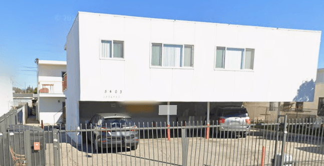 A white building with a black car parked in front of it.